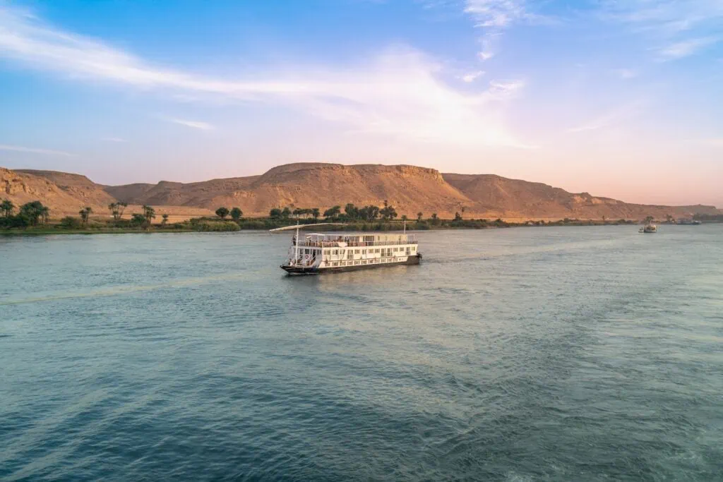 Dahabiya sailing vessel on the Nile River near Esna Lock at dusk, the traditional twin-mast cruise alternative on the Luxor–Aswan route.