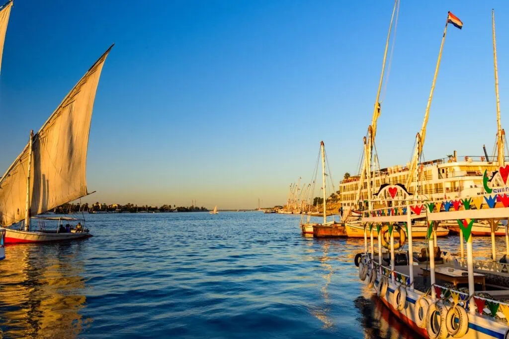 Feluccas sailing beside a large Nile cruise ship