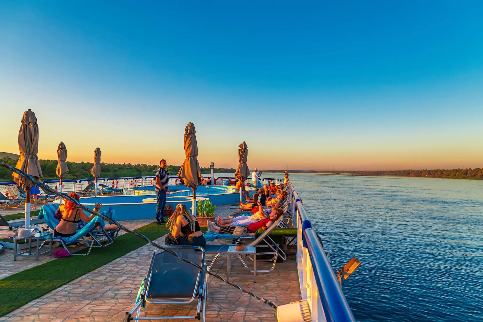 Sunset view from Nile River cruise ship deck with passengers and chairs