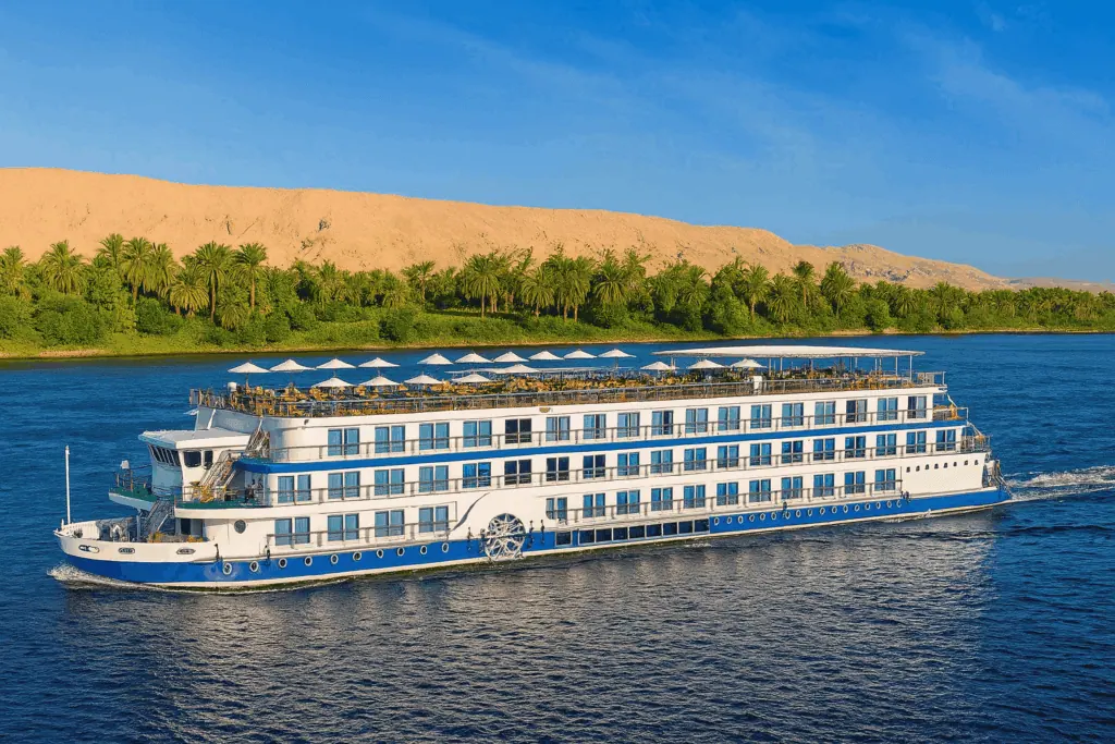 A 5-star Luxury Nile Cruise vessel sailing the Nile between Luxor and Aswan, with the river bank and desert visible in the background, Egypt.