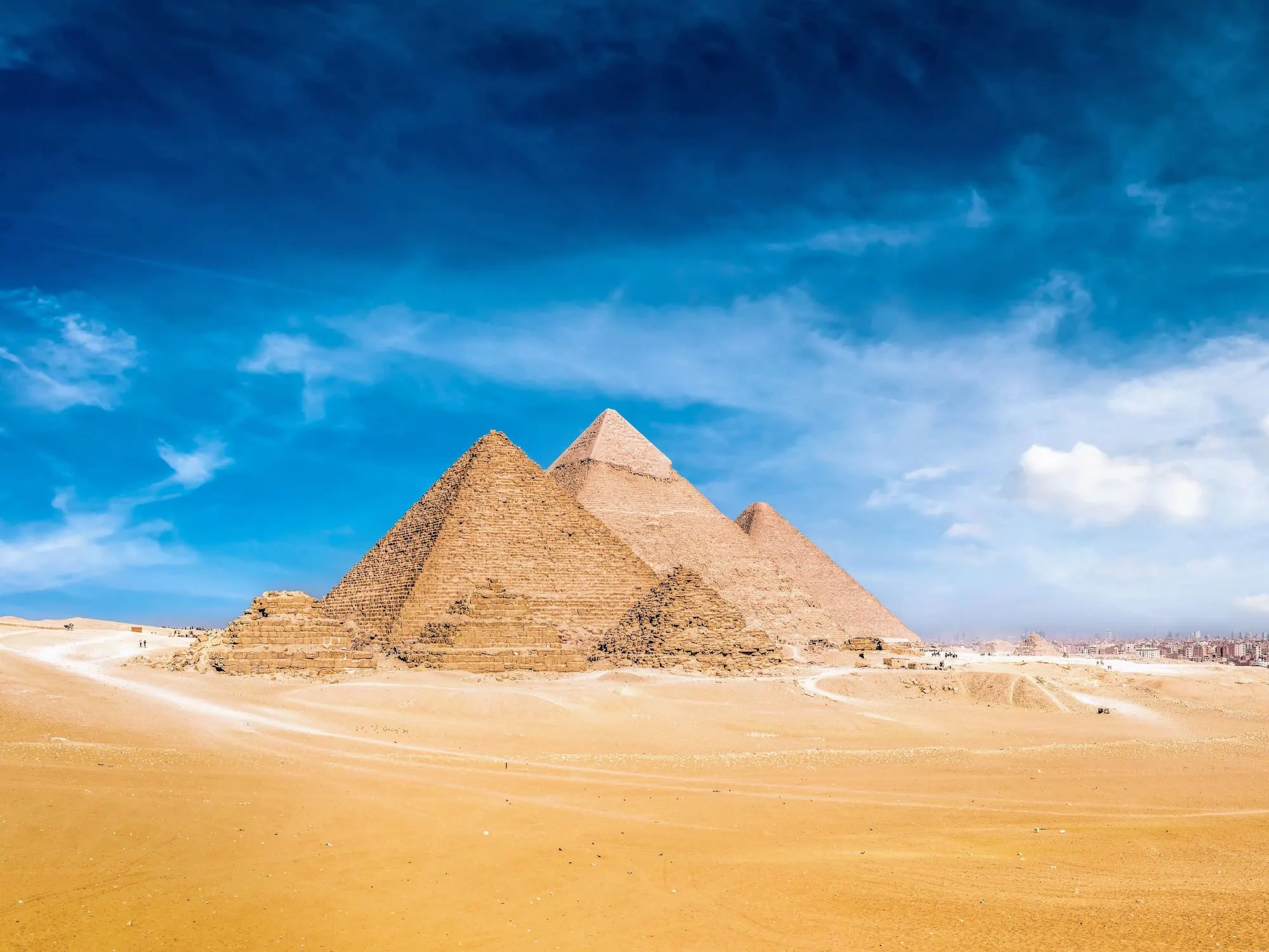 Panoramic view of the three Pyramids of Giza on the Giza Plateau outside Cairo, Egypt — Khufu (the Great Pyramid, c. 2580 BC), Khafre (c. 2570 BC), and Menkaure (c. 2510 BC), built by three successive 4th-dynasty pharaohs