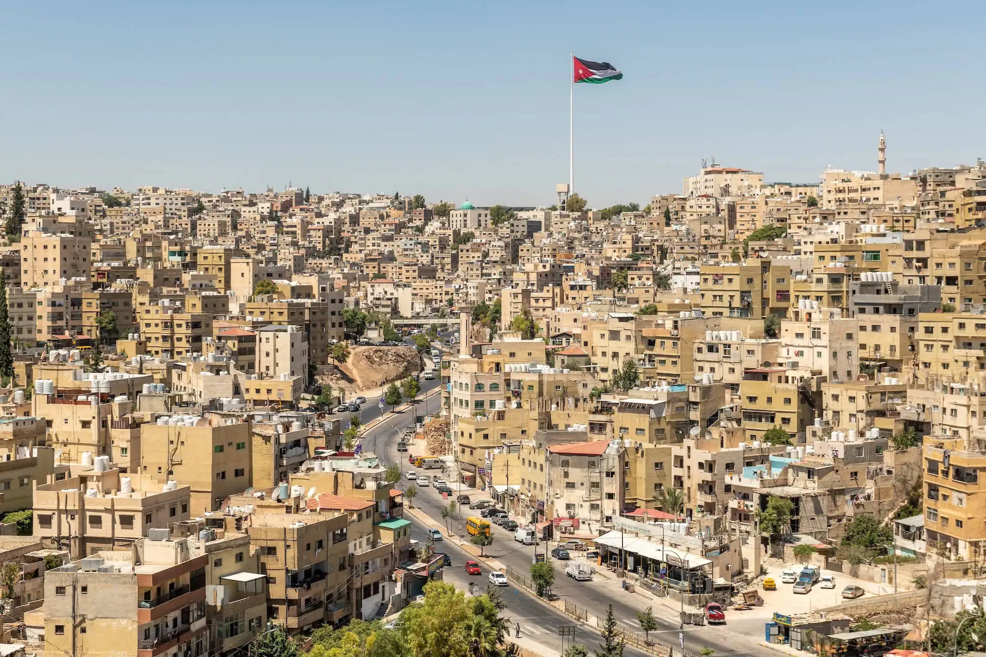 Panoramic view of Amman cityscape with Jordanian flag on flagpole