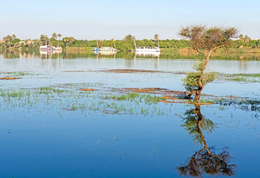 Panoramic landscape view across nile river to luxor west bank with mountains and reflection in water