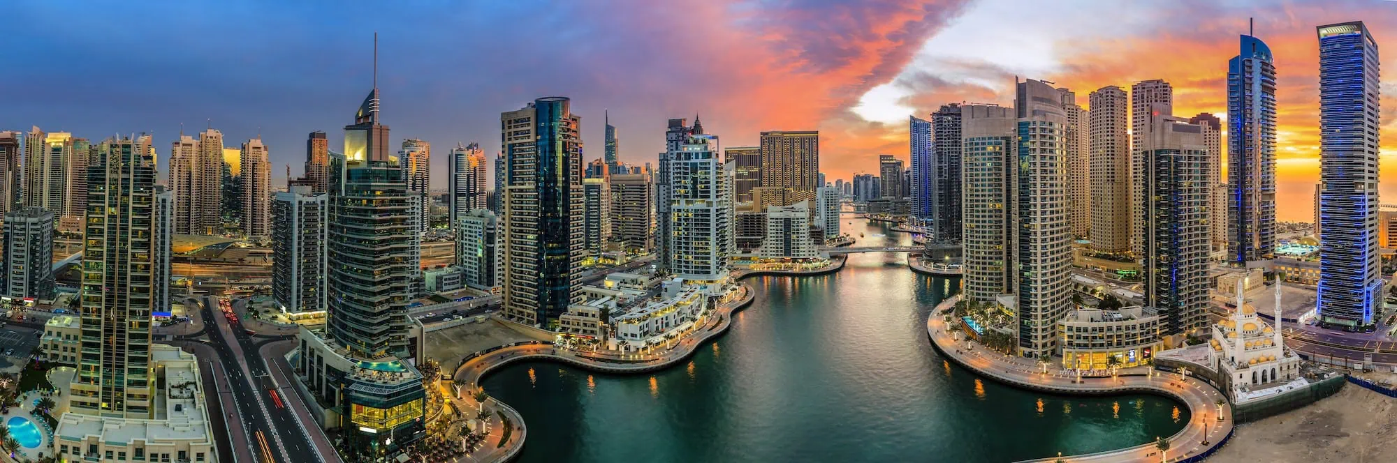 Panoramic aerial view of Dubai Marina district at sunset with modern skyscrapers and marina