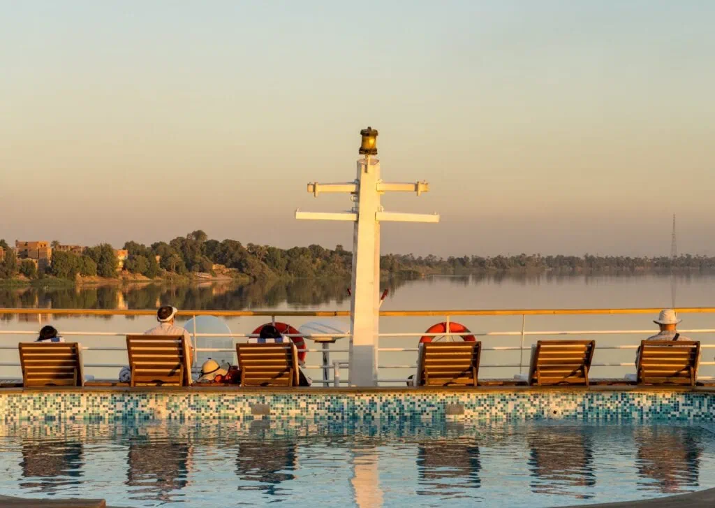 Passengers relaxing on deck chairs beside a swimming pool on a Nile River cruise ship deck, Nile River Cruise Ship