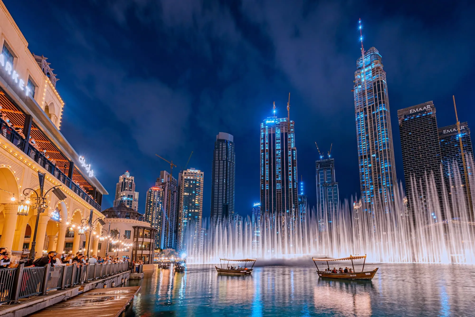 Dubai Fountain water show at night with traditional boats and tourists