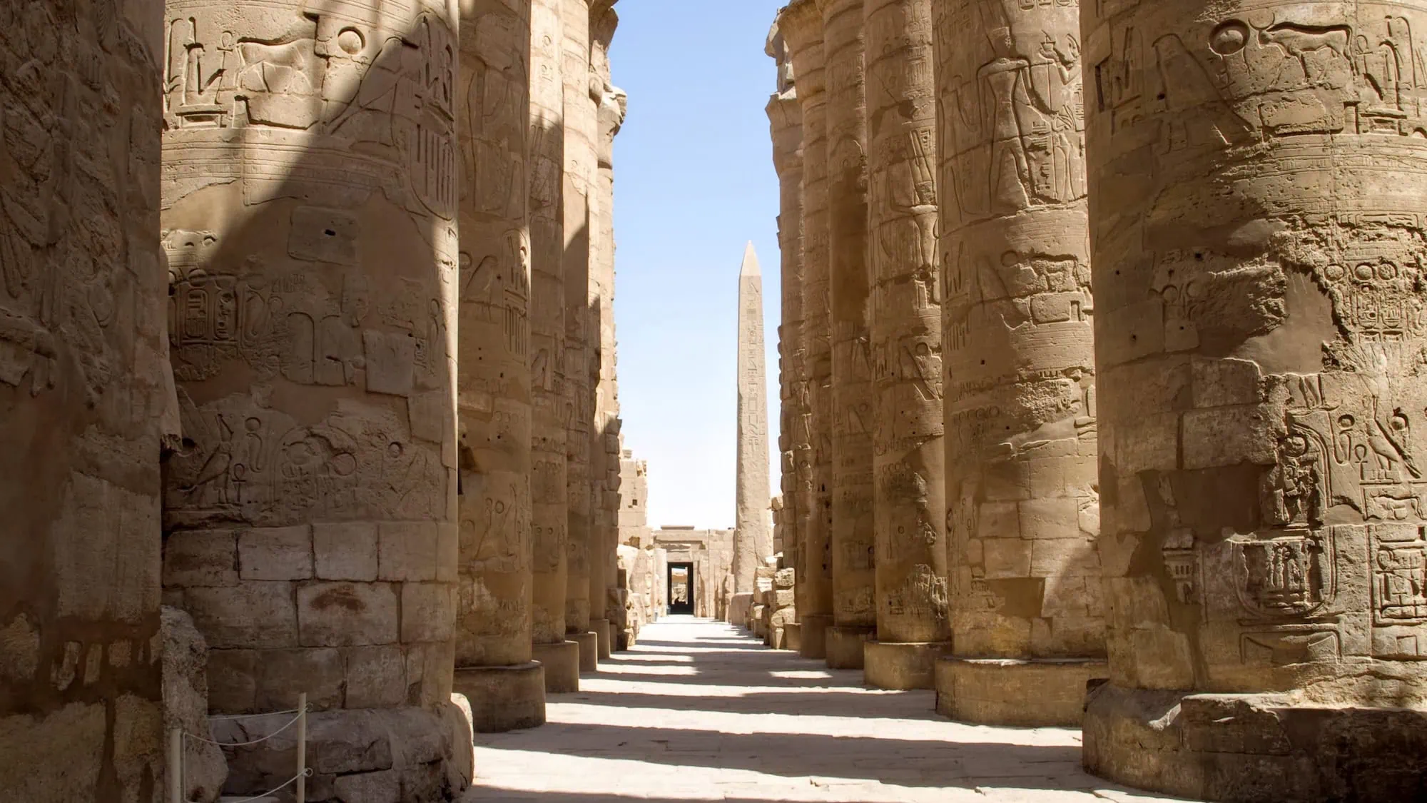 Ancient Egyptian temple complex with towering columns, hieroglyphic carvings, and obelisk at Karnak