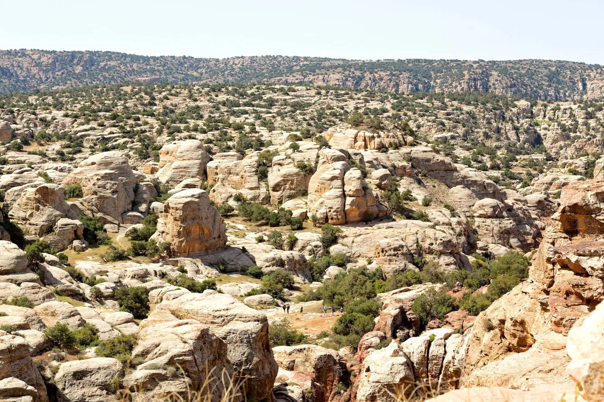 Hikers walking through dramatic sandstone formations in Dana Biosphere Reserve, Jordan
