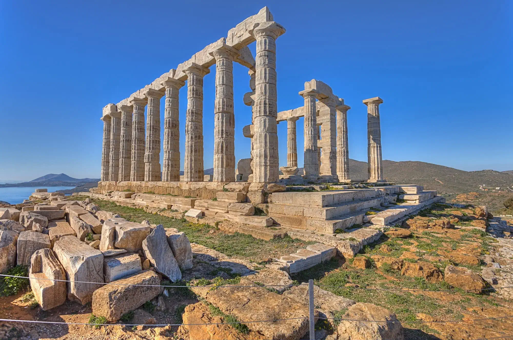 The 5th-century BC Doric columns of the Temple of Poseidon at Cape Sounion, Greece — clifftop temple ruins overlooking the Aegean Sea, 70 km south of Athens, with 15 of the original 34 columns still standing
