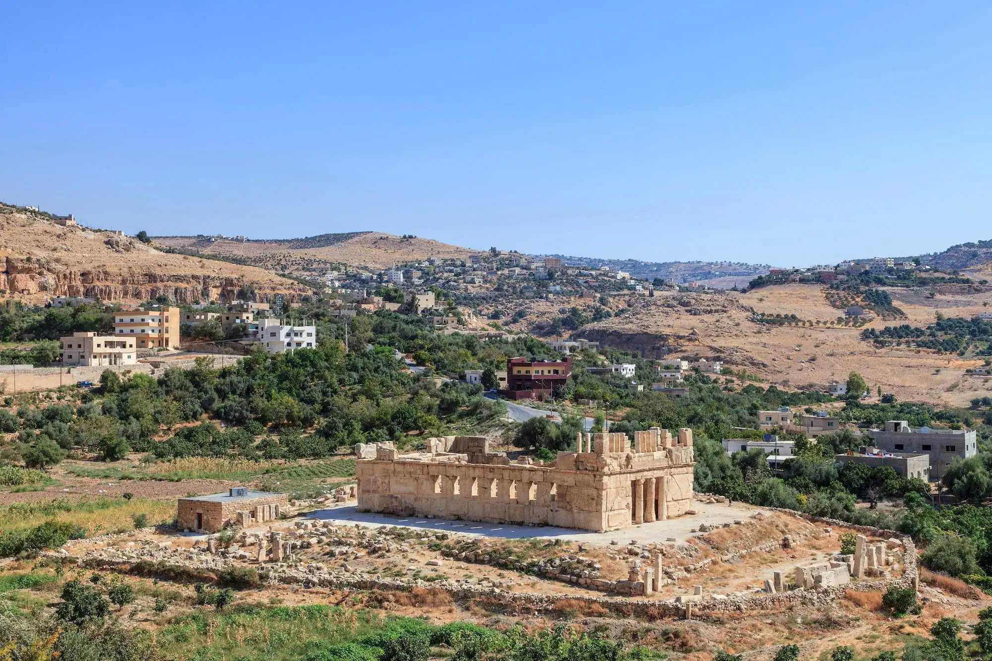 Ancient Qasr al-Abd palace ruins with limestone walls and columns in valley landscape