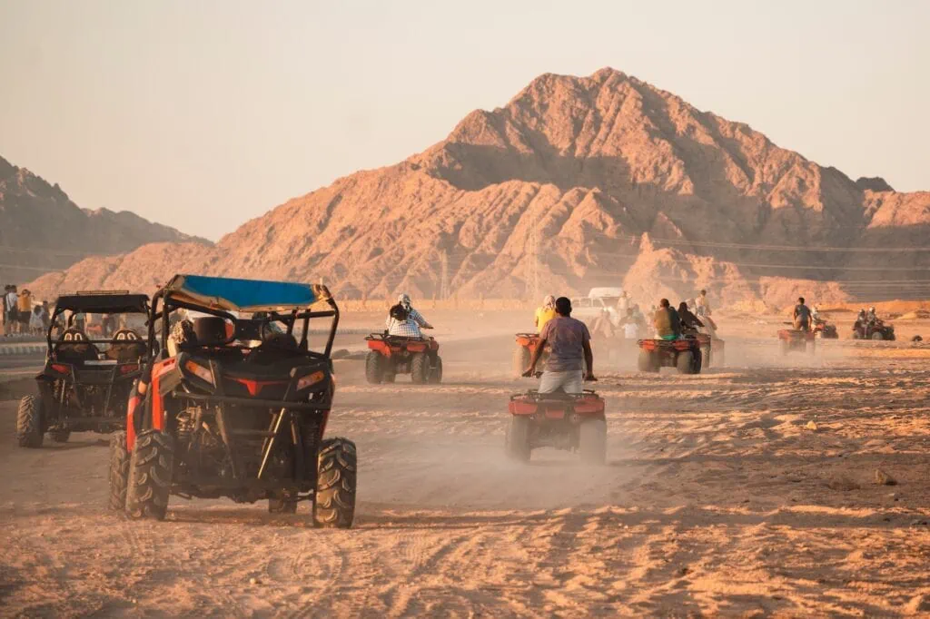 Tourists on quad bikes crossing the dunes of the Eastern Desert in Egypt during a half-day excursion from a Red Sea coastal resort