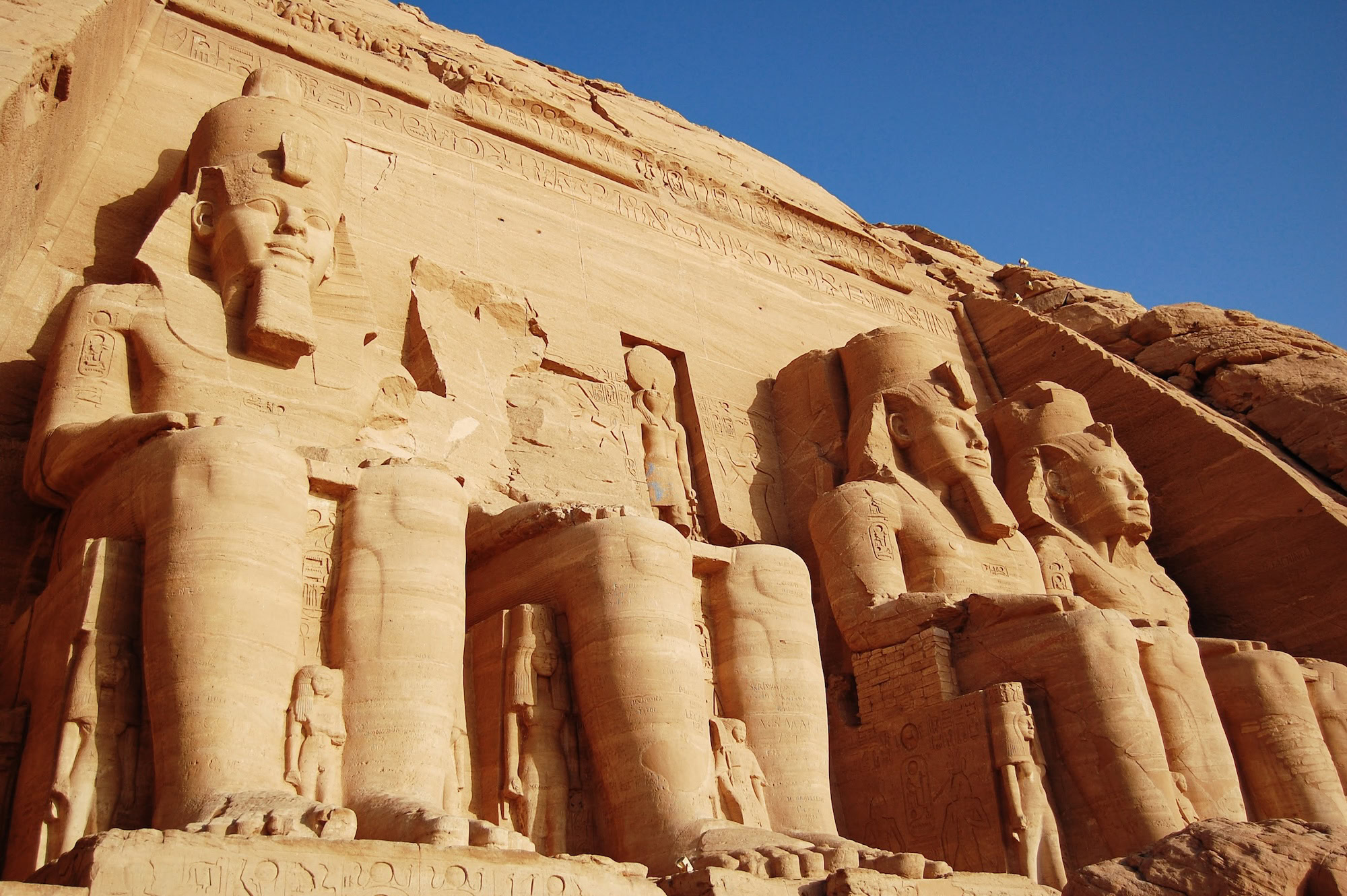Colossal pharaoh statues at Abu Simbel temple facade carved into sandstone cliff