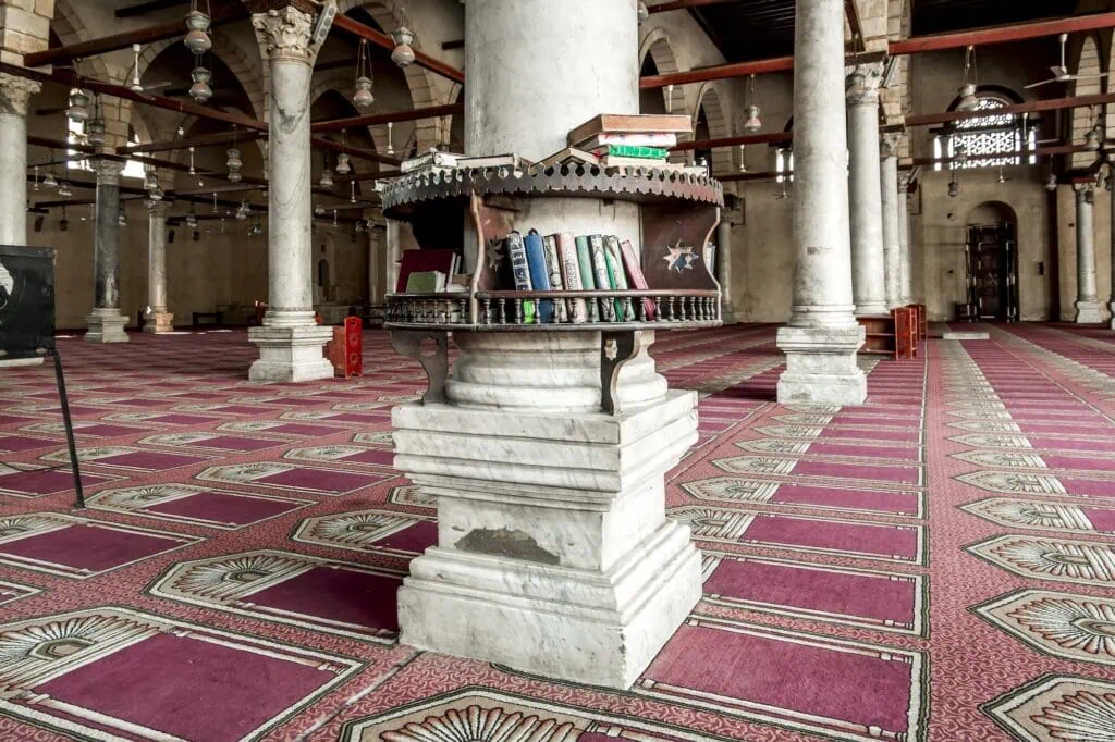 Shelves displaying religious books and copies of the Quran inside the Mosque of Amr ibn al-As, Cairo