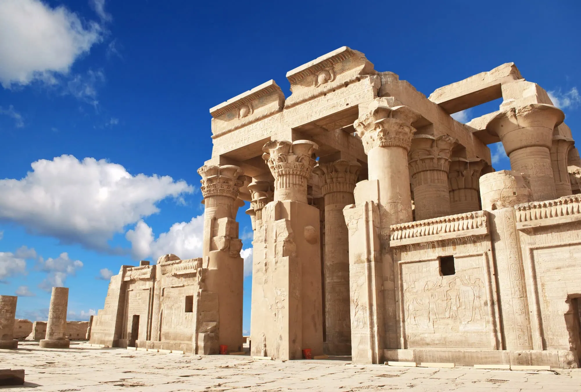 Ancient columns of Kom Ombo Temple with hieroglyphics against blue sky