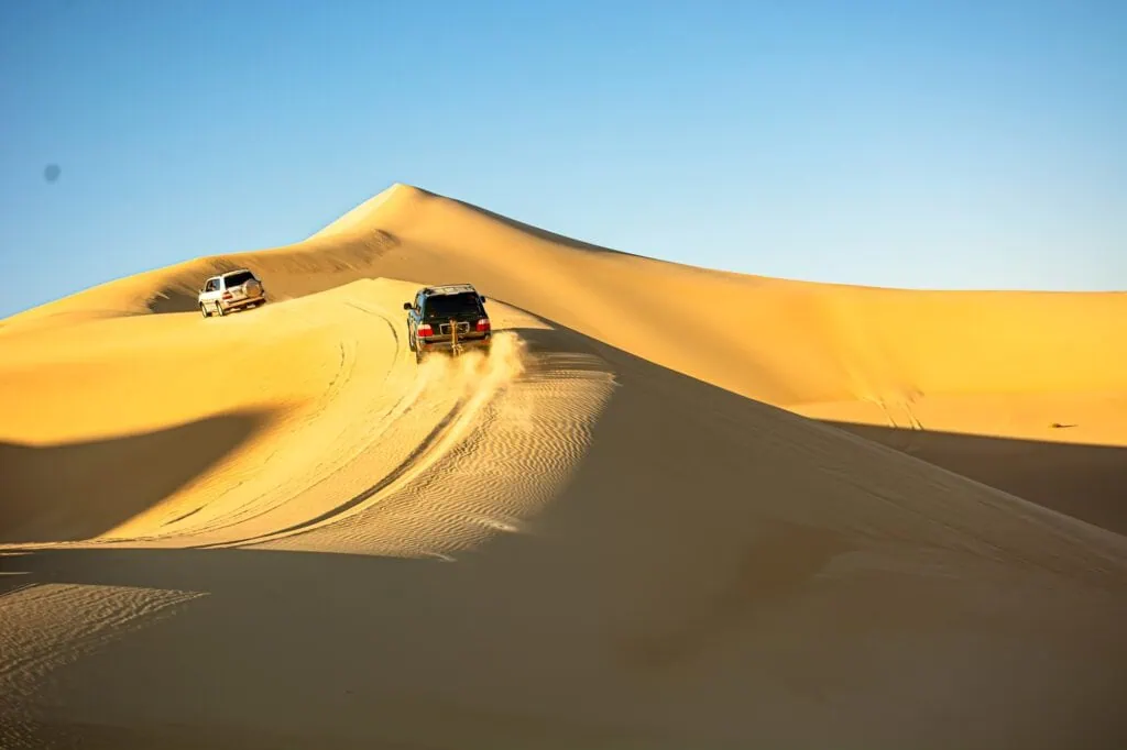 Four-wheel-drive vehicle crossing high sand dunes during a desert safari, Great Sand Sea, Siwa Oasis