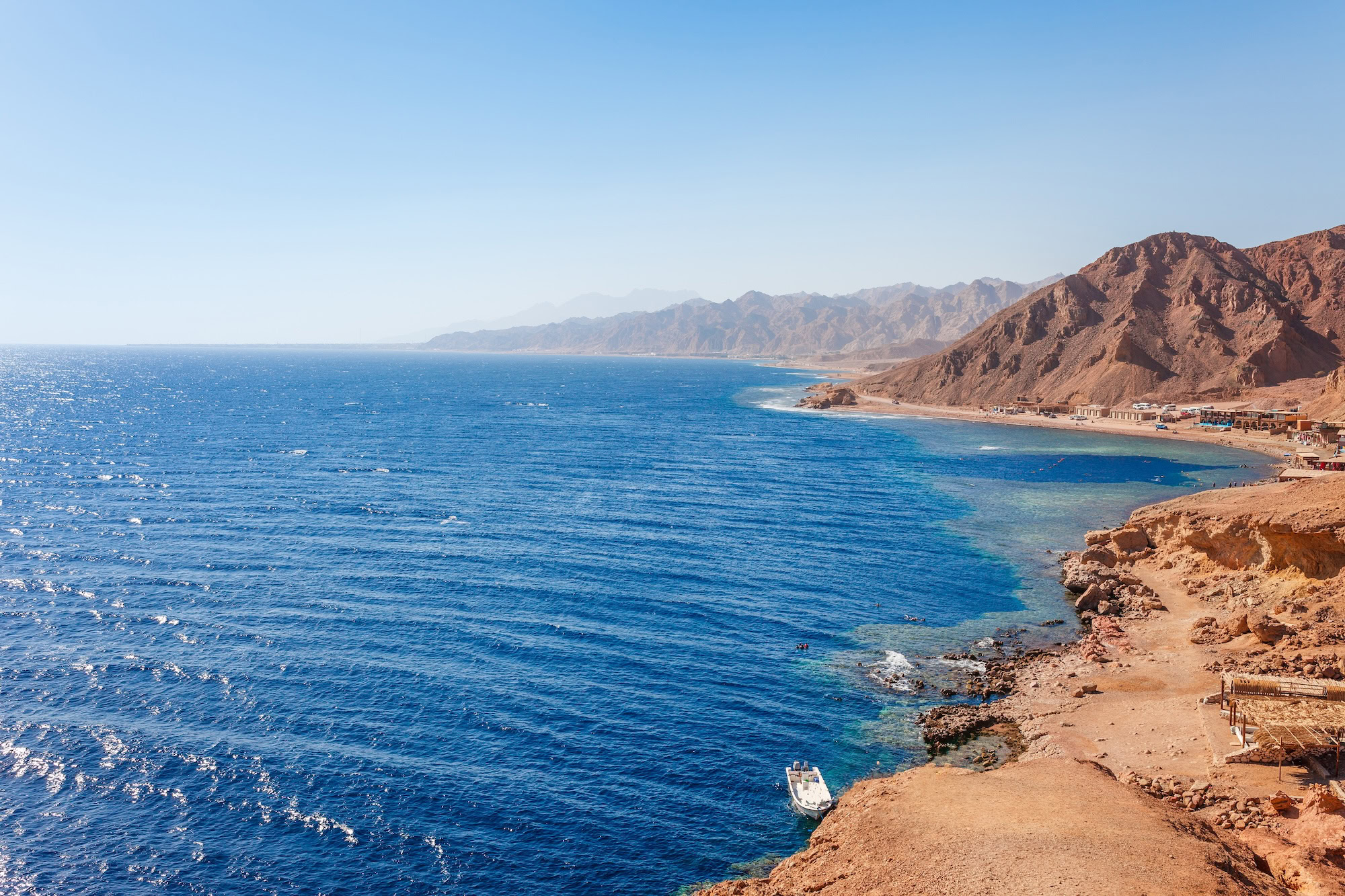 Serene Red Sea coastline with clear turquoise water, mountains, and resort buildings