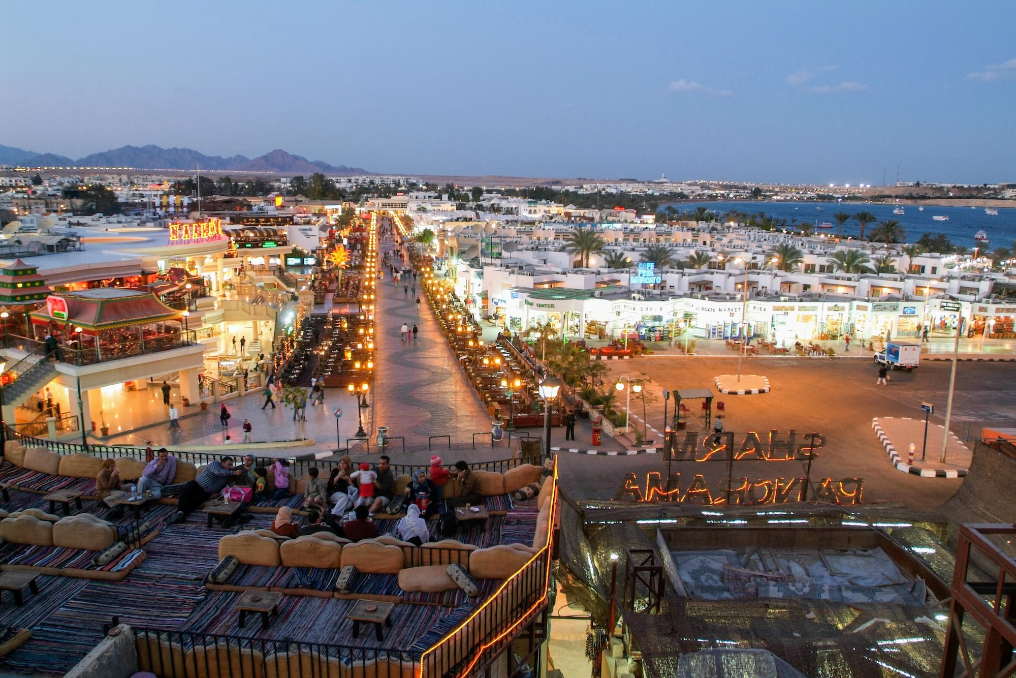 Aerial view of Naama Bay promenade with shops, restaurants, palm trees and boats