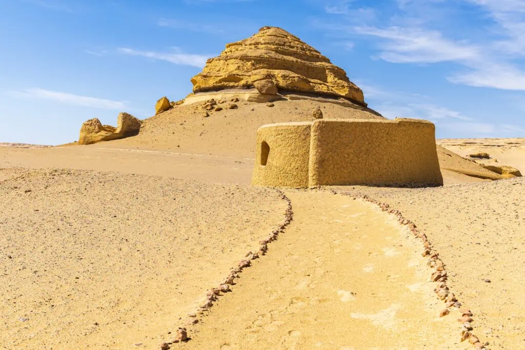 Small stone building beside sandy trail at Wadi el-Hitan