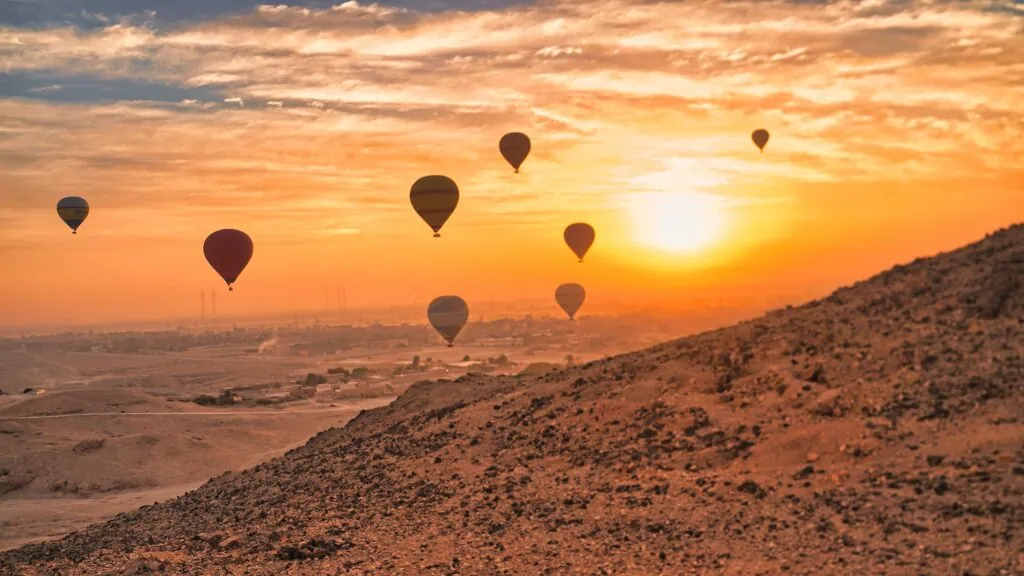 Silhouettes of hot air balloons against the bright morning sun in the early light over Luxor, Egypt.