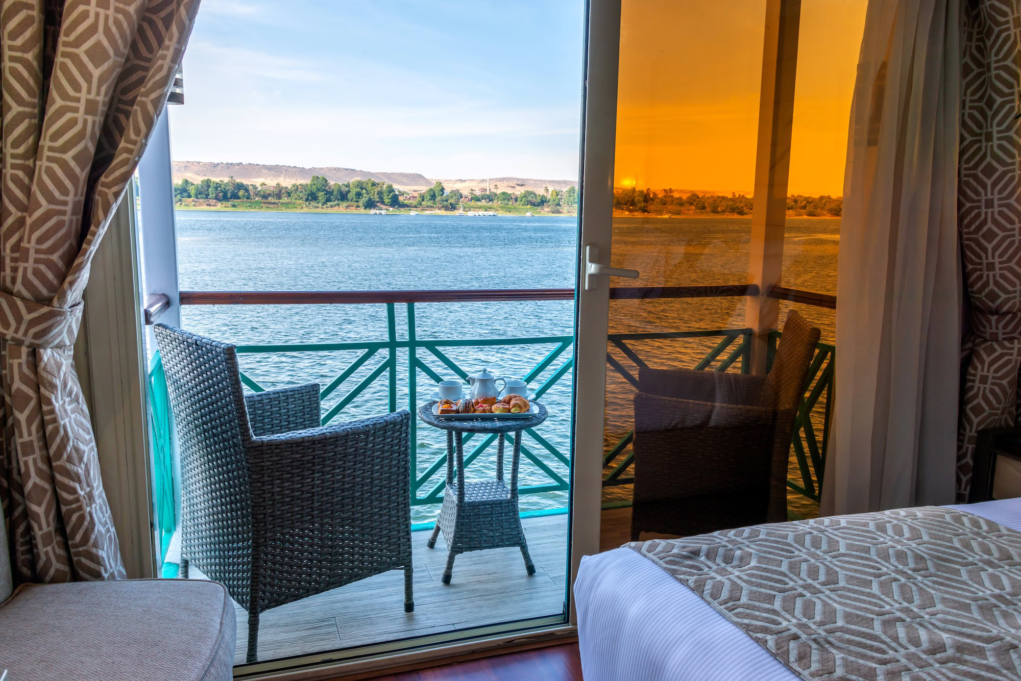 Luxury Nile River cabin interior with private balcony and panoramic windows showing desert landscape view