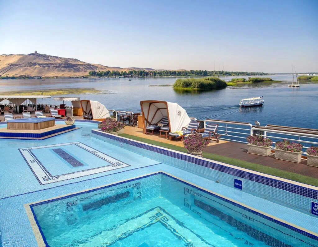 The swimming pool and sun deck with loungers aboard a Luxury Nile Cruise vessel sailing the Nile between Luxor and Aswan, Egypt.