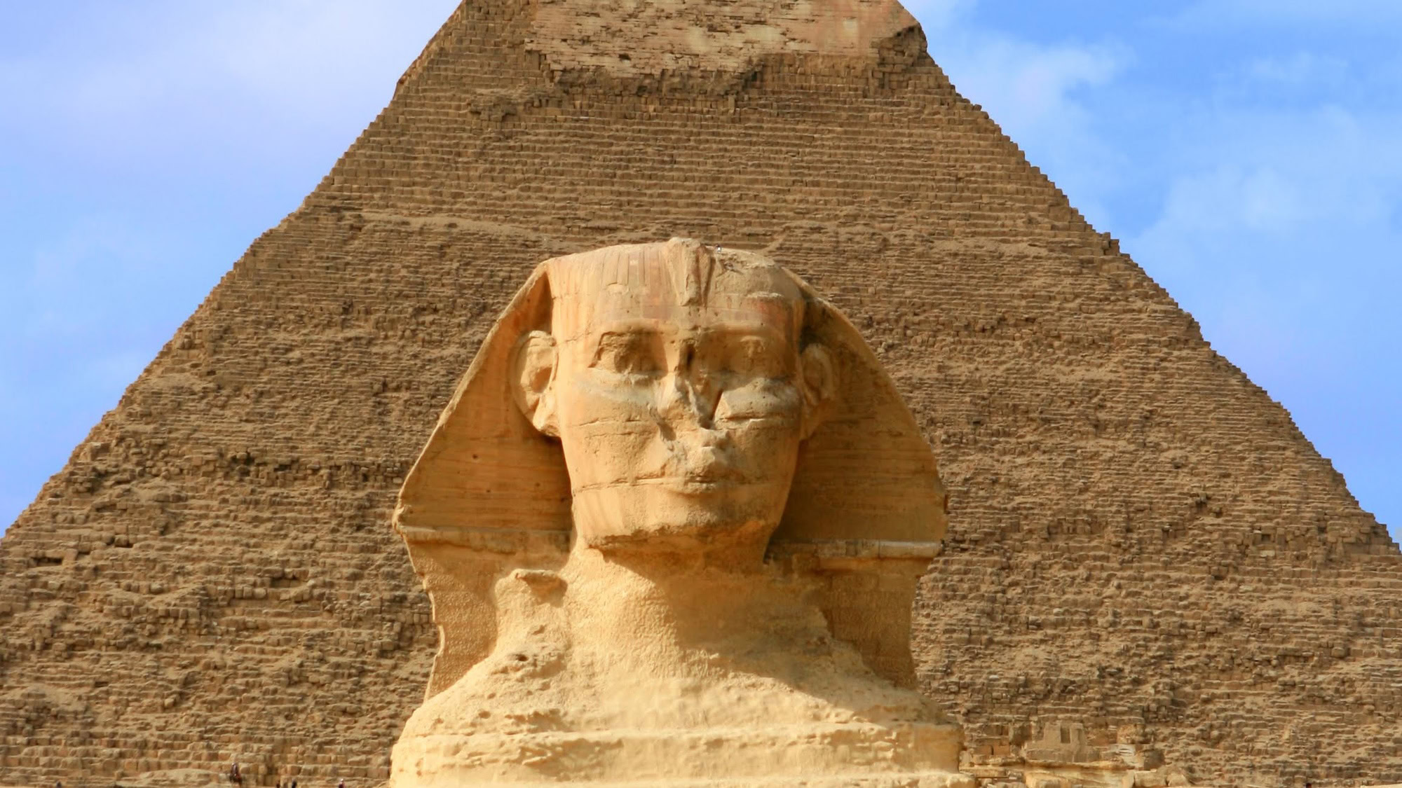 Great Sphinx of Giza with pyramid in background under cloudy sky