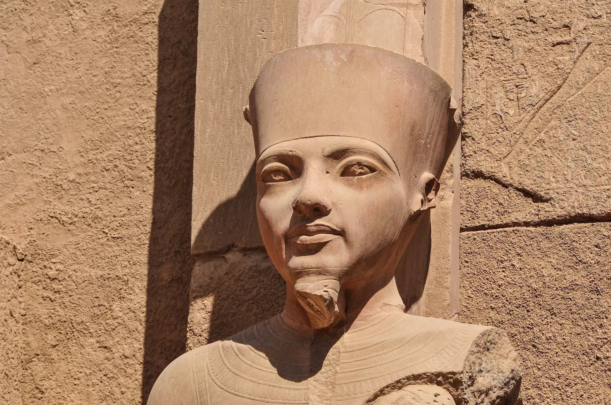 Ancient Egyptian pharaoh statue carved in stone with ceremonial headdress and hieroglyphic carvings