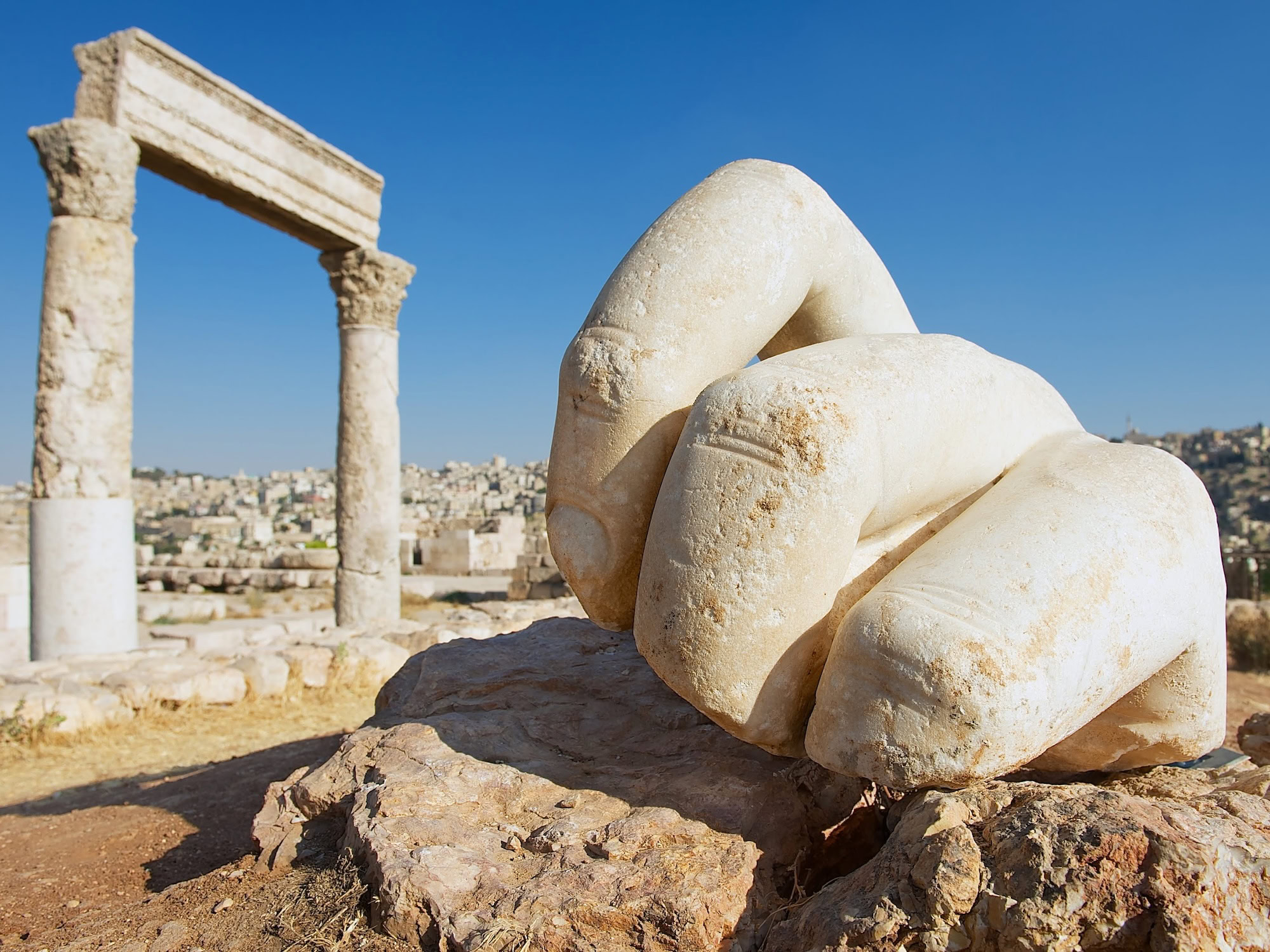 Ancient marble hand sculpture and Roman columns at Amman Citadel archaeological site
