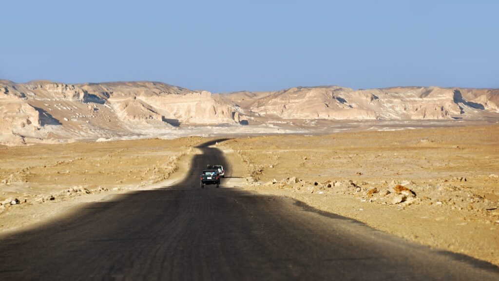 Paved road passing through sand dunes and sandstone formations in Farafra Oasis