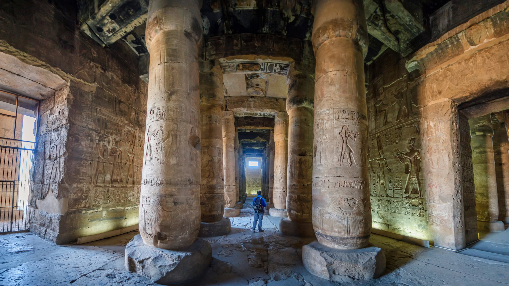 Person inside ancient Egyptian temple with columns and hieroglyphic walls
