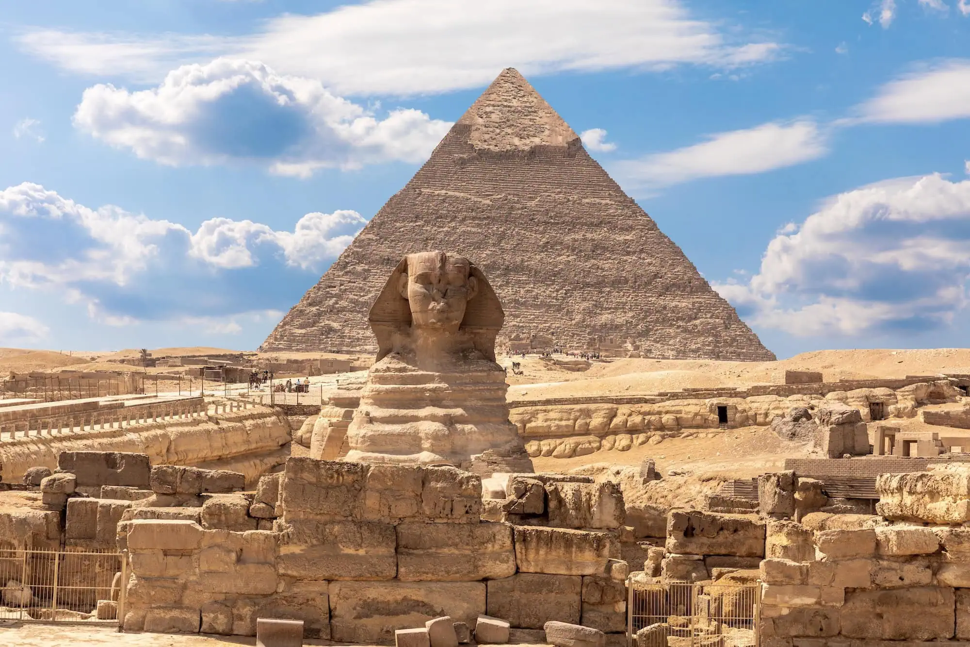 The Great Sphinx of Giza in profile with the Pyramid of Khafre rising directly behind and the granite-block walls of the Valley Temple in the foreground
