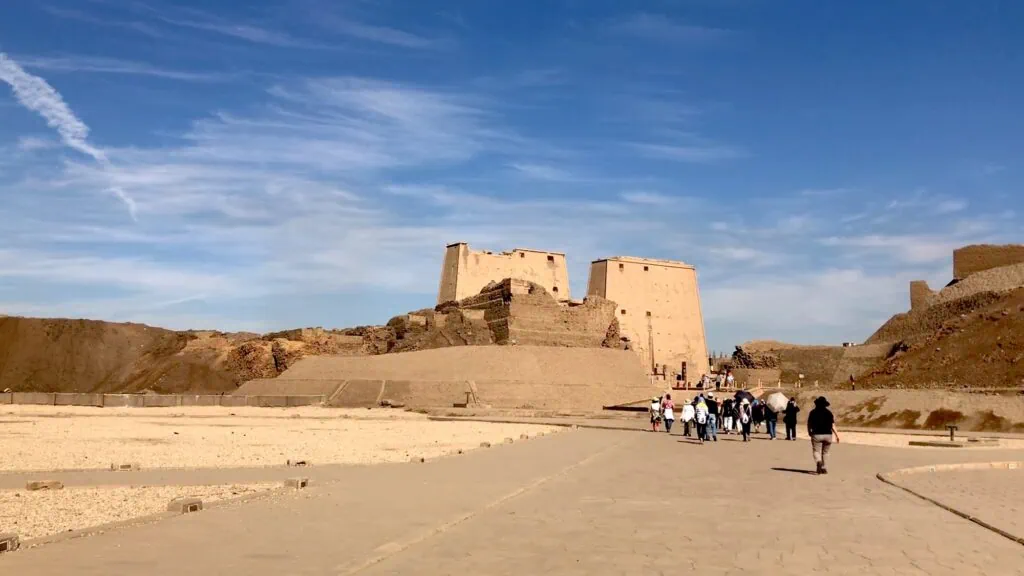 Distant view of Edfu Temple entrance with visitors walking toward the pylon, Edfu