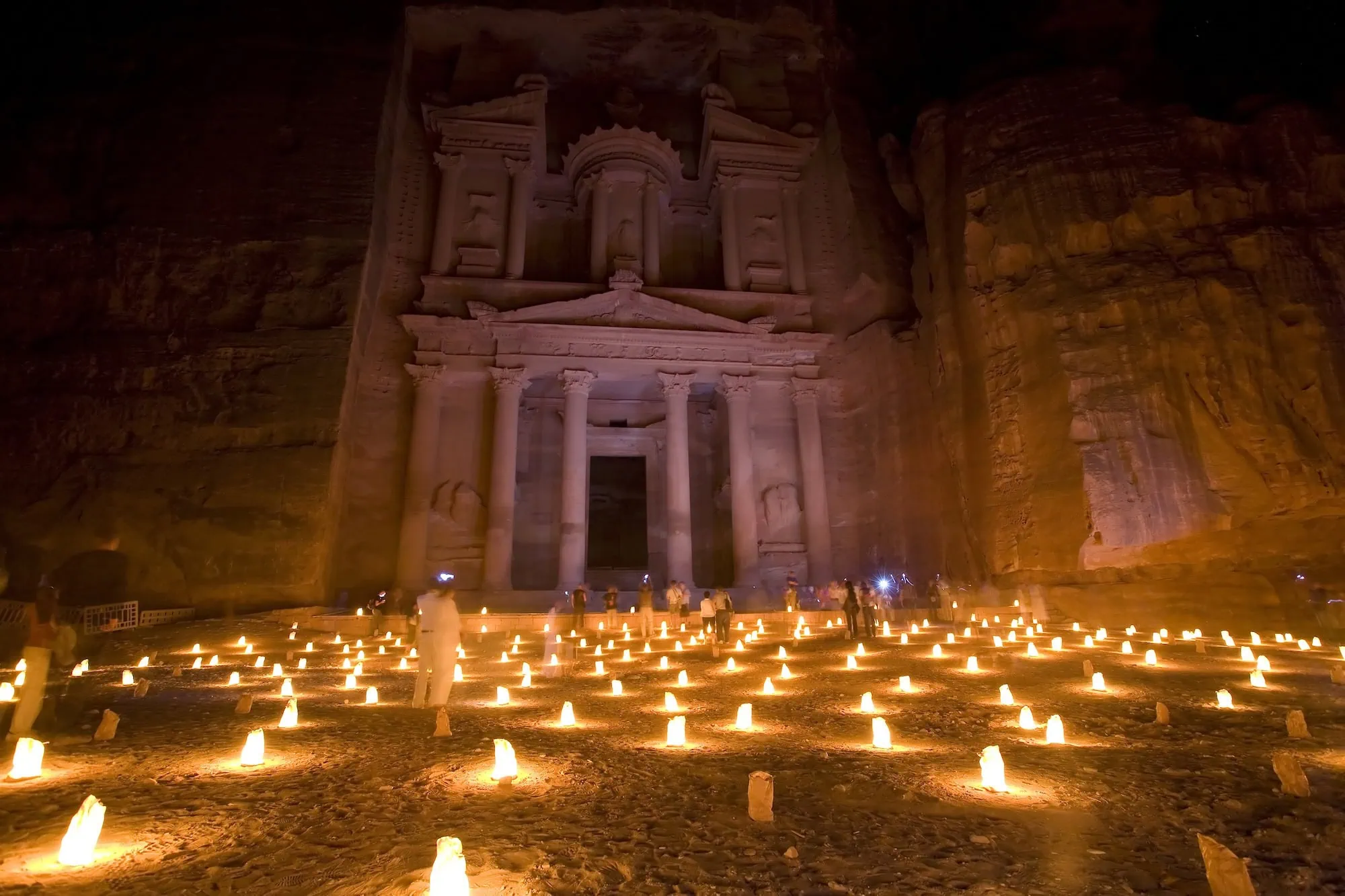 Al-Khazneh (The Treasury) at Petra, Jordan, illuminated by 1,500 candles during the Petra by Night experience — the famous Nabataean rock-cut facade at the end of the Siq canyon, carved in the 1st century BC