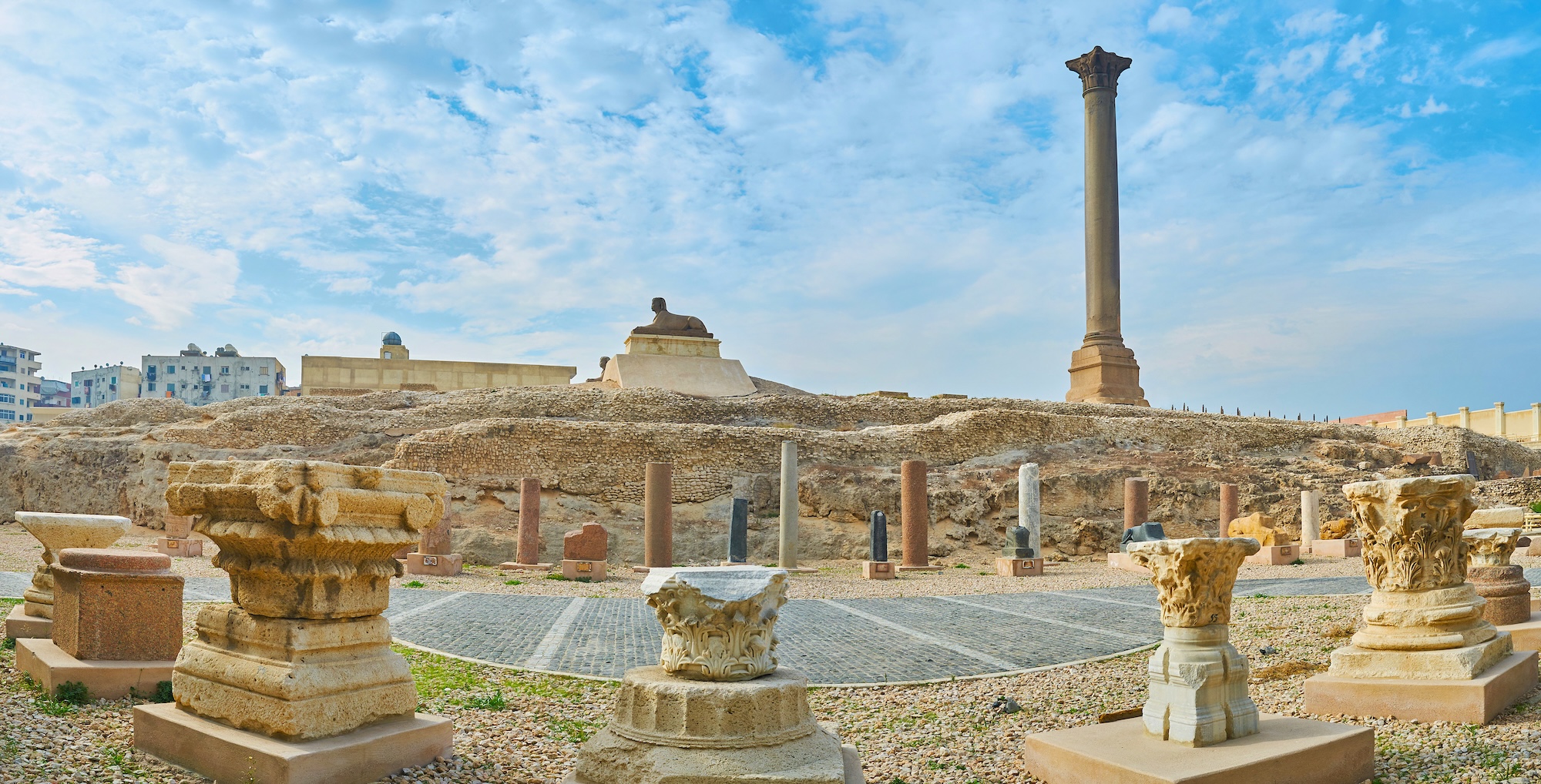 Pompey's Pillar ancient Roman column with sphinx and archaeological ruins in Alexandria