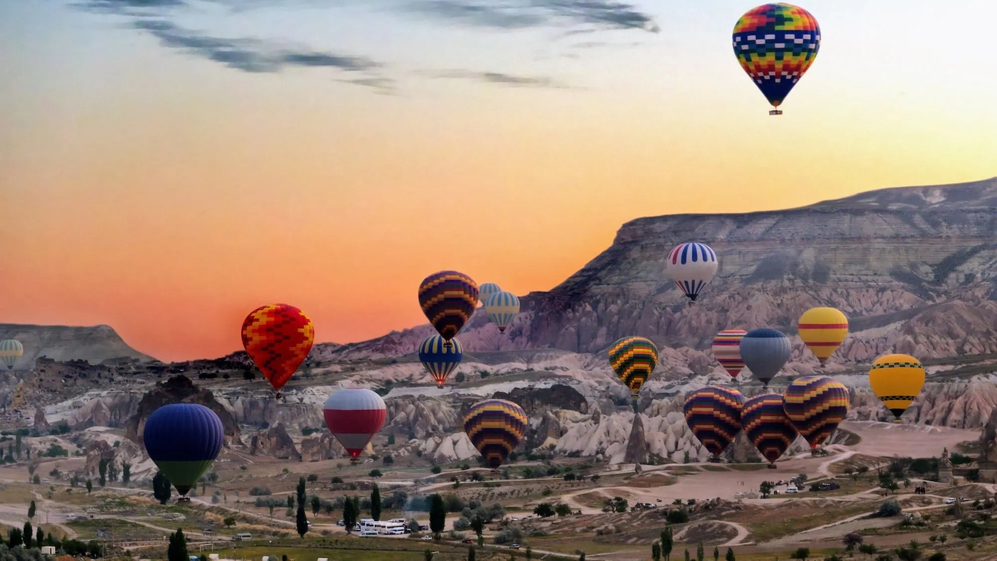 Hot air balloons floating over Cappadocia's fairy chimney rock formations at sunrise