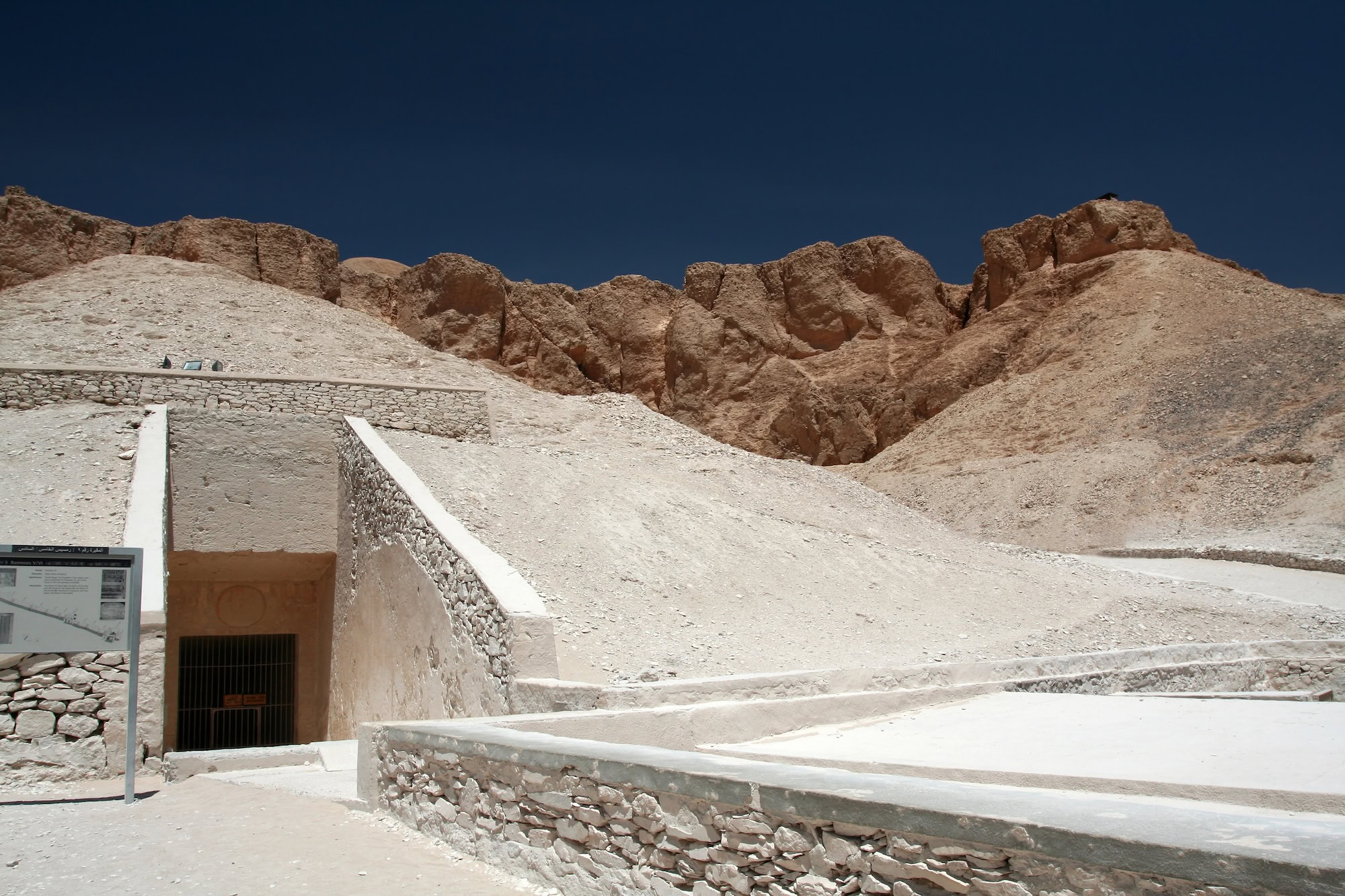 Ancient tomb entrance in Valley of the Kings with stone stairs and protective barriers