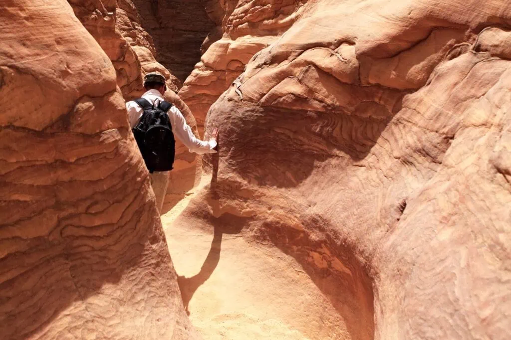 Tourist walking through narrow sandstone walls in Colored Canyon, Nuweiba