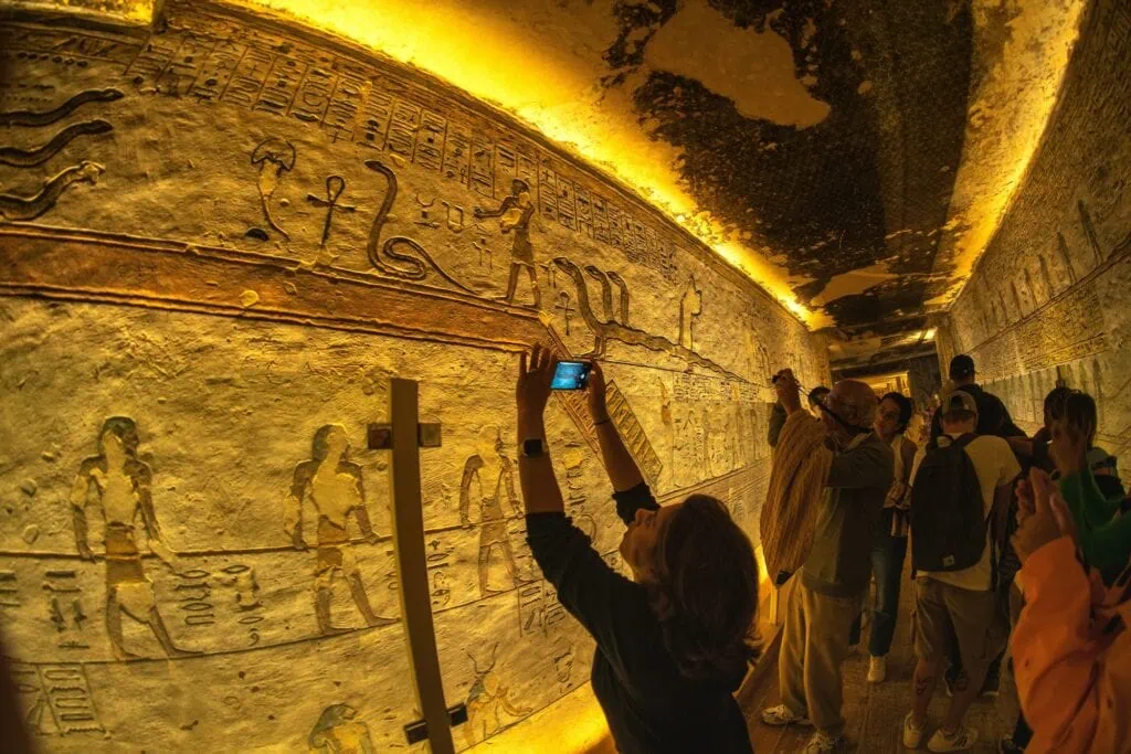 Tourists photographing with phones among tomb entrances at the Valley of the Kings, Luxor