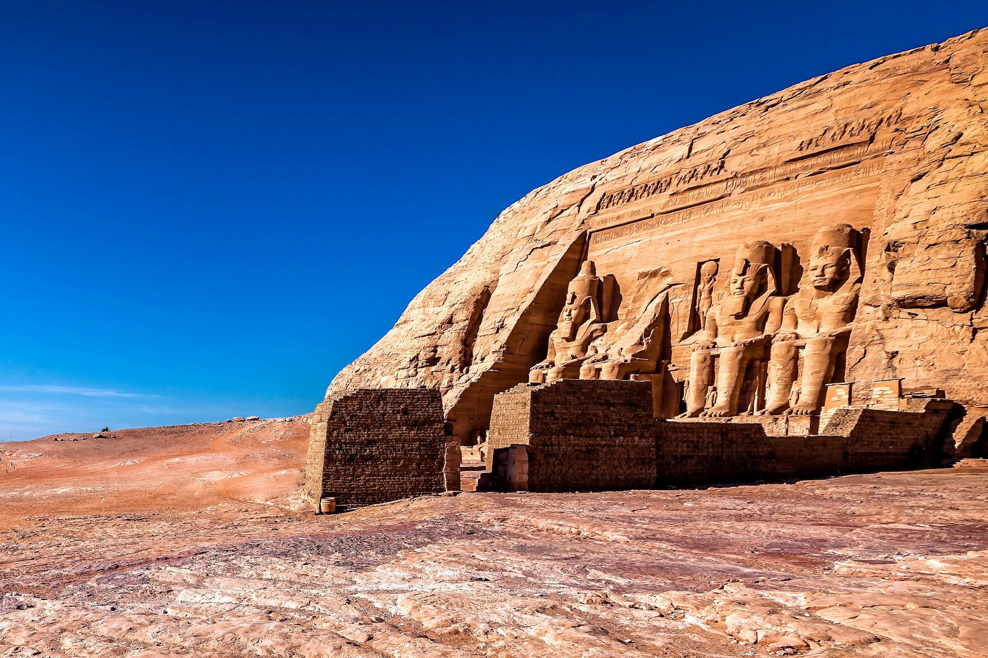 Abu Simbel Temple facade with four colossal pharaoh statues carved into sandstone cliff