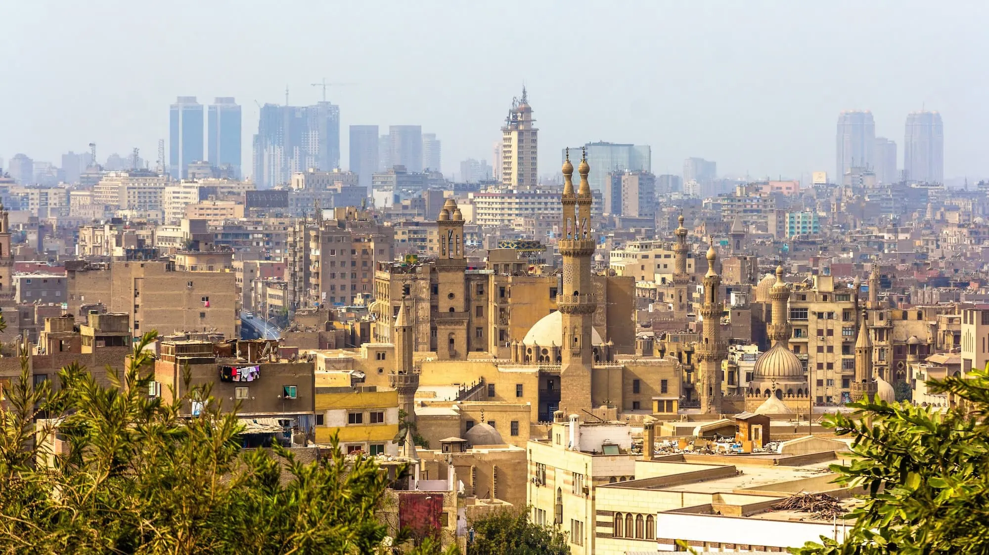 Panoramic view of medieval Islamic Cairo with mosque minarets, stone domes, and traditional architecture rising across the Egyptian capital's historic core