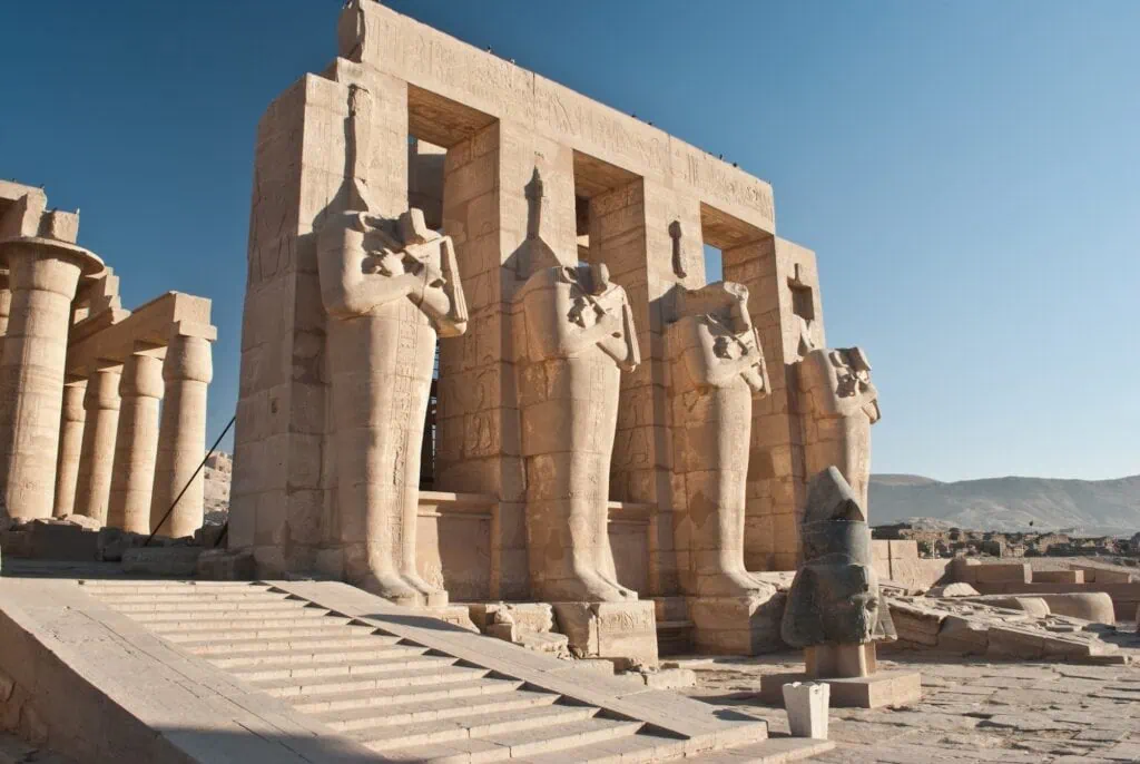 Standing Osiris statues carved in stone among the ruins of the Temple of Ramesses II at the Ramesseum, Luxor
