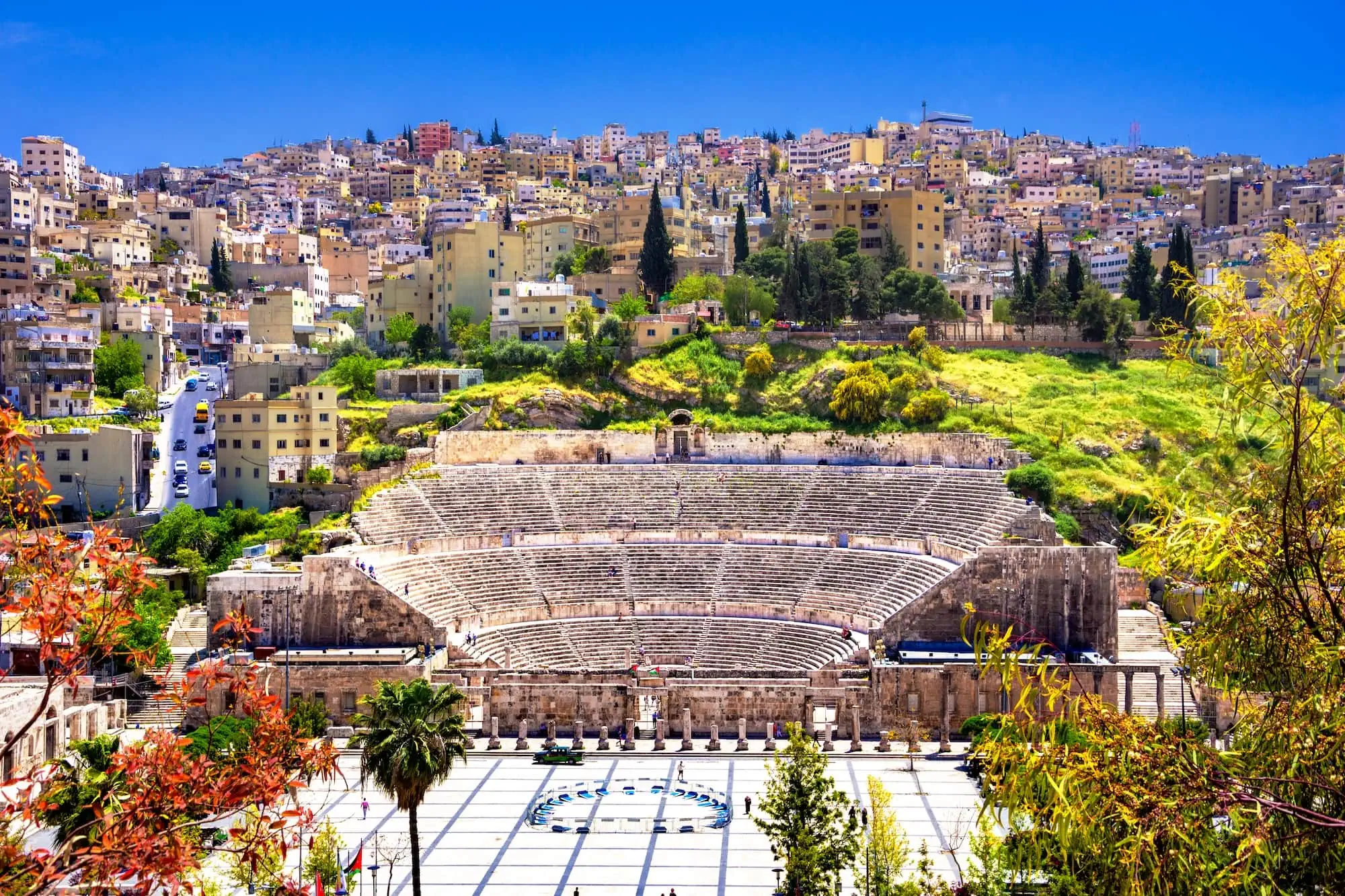 Roman Theater amphitheater surrounded by Amman's modern cityscape and hillside buildings