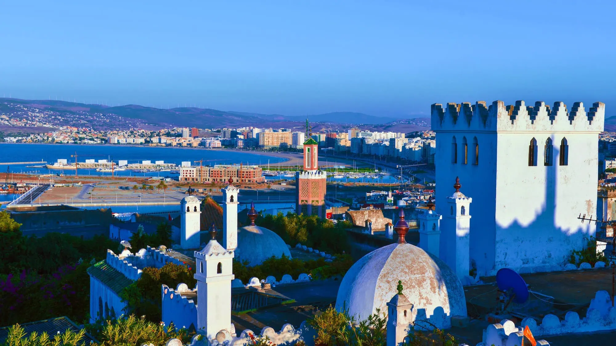 Aerial view of Tangier's historic Kasbah showing traditional Islamic architecture with white buildings, mosques, and domed structures