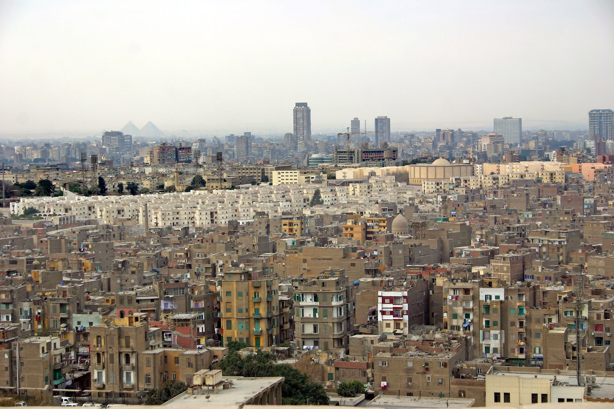 Vista aérea do Cairo com pirâmides de Gizé e edifícios urbanos modernos