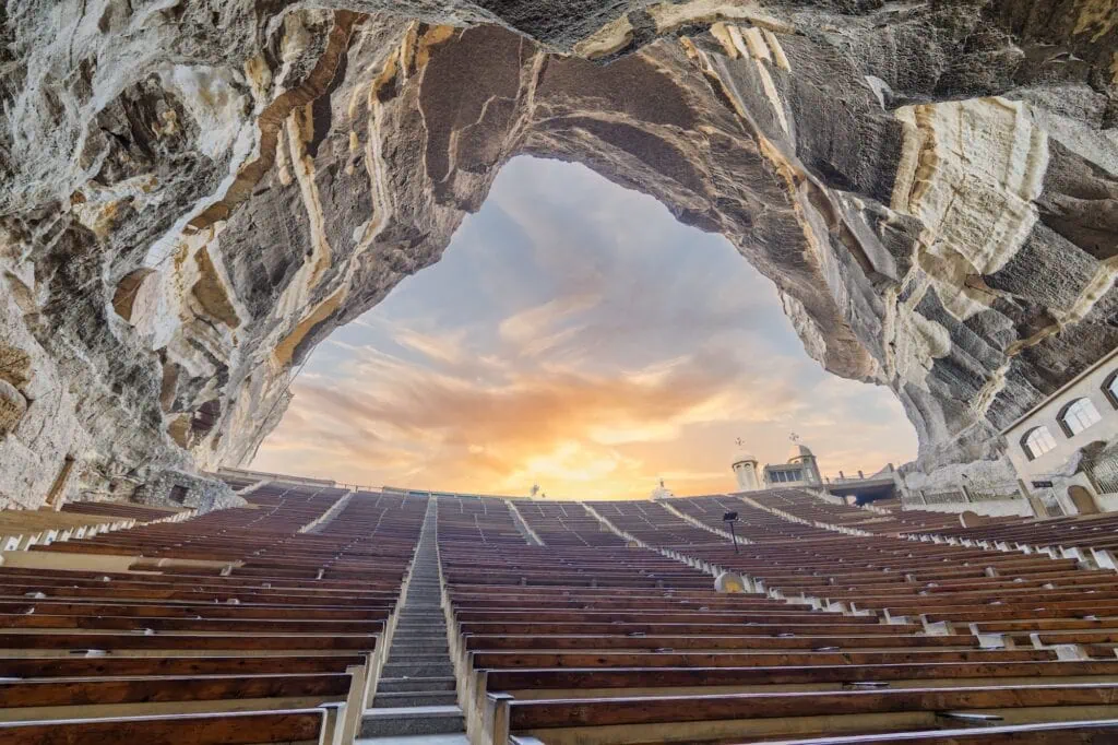 The large rock-carved interior with stepped seating and carved stone walls inside Saint Simon the Tanner Cathedral