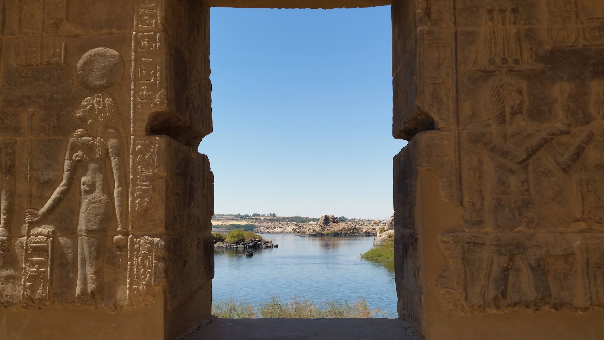 Ancient Egyptian temple with columns and hieroglyphics alongside the Nile River