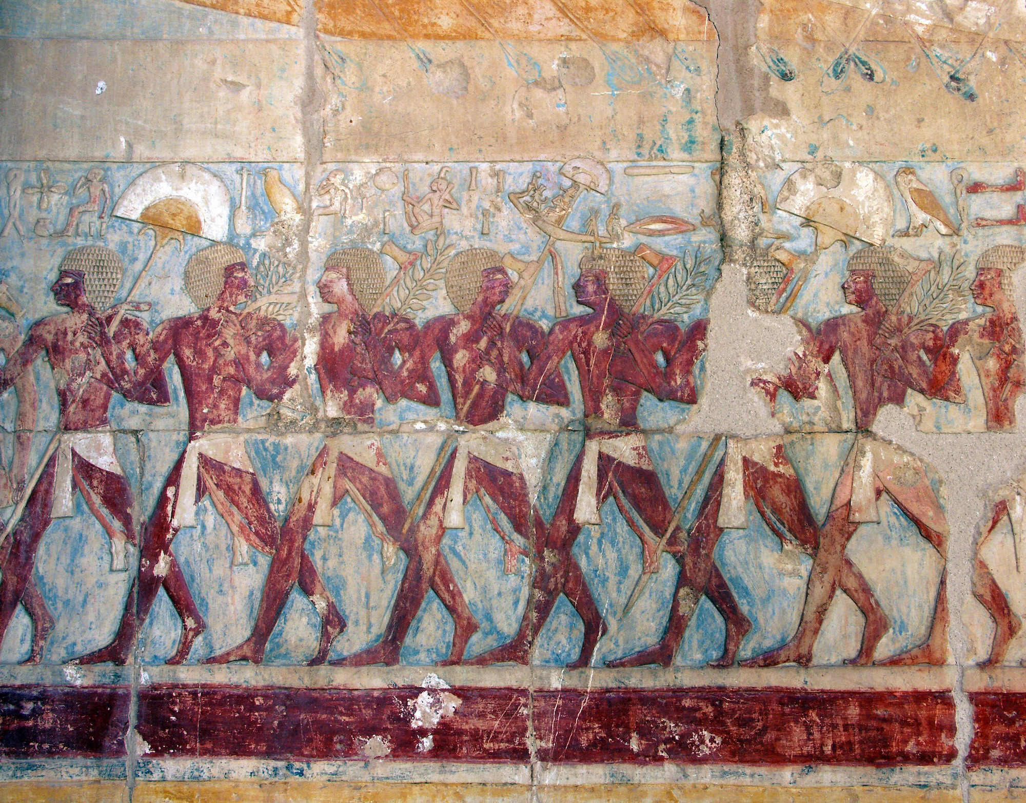 Ancient Egyptian mastaba tomb wall painting showing figures in procession carrying baskets and offerings