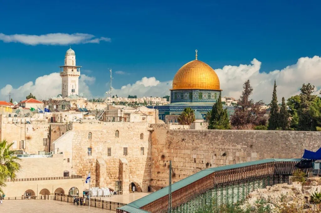 View of the Western Wall plaza with the gold-domed Dome of the Rock rising above on the Temple Mount, Old City of Jerusalem, Israel — the holiest site in Judaism beneath one of the holiest sites in Islam
