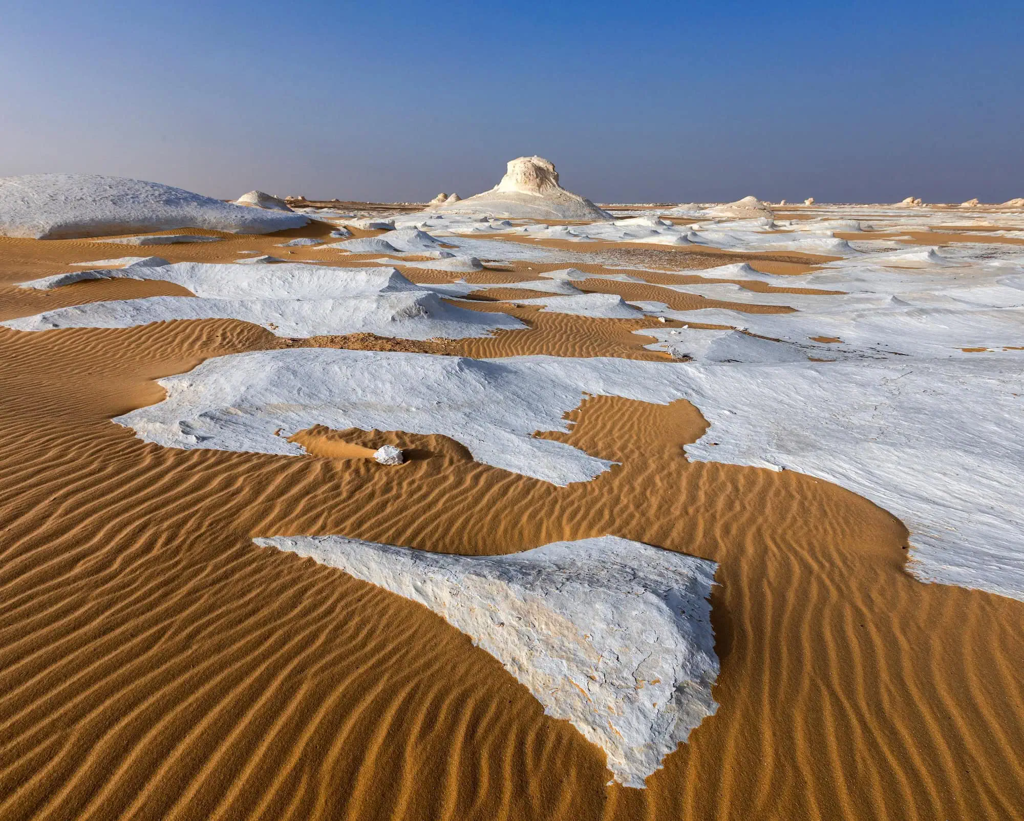 Wind-eroded white limestone formations in Egypt's White Desert at sunset