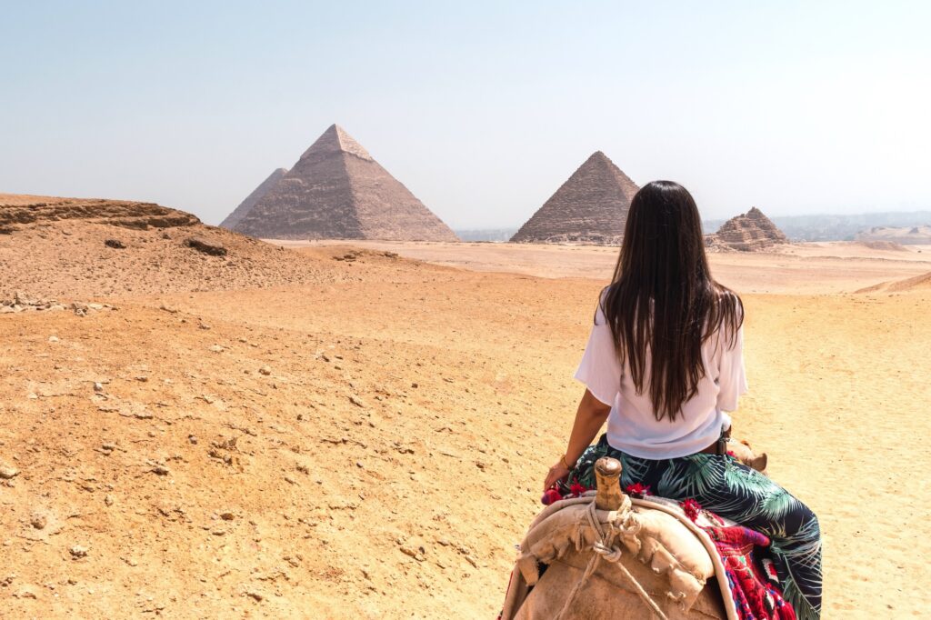 Woman riding a dromedary, gazing at the pyramids of Egypt – a memorable moment on Egypt tours from Edmonton.